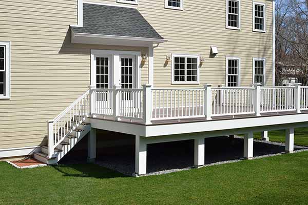 Small deck with white railings on the back of a beige home