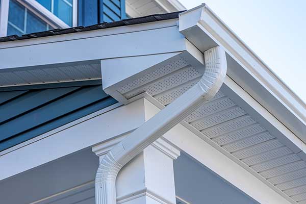 White, k-style gutters with a downspout on a fascia